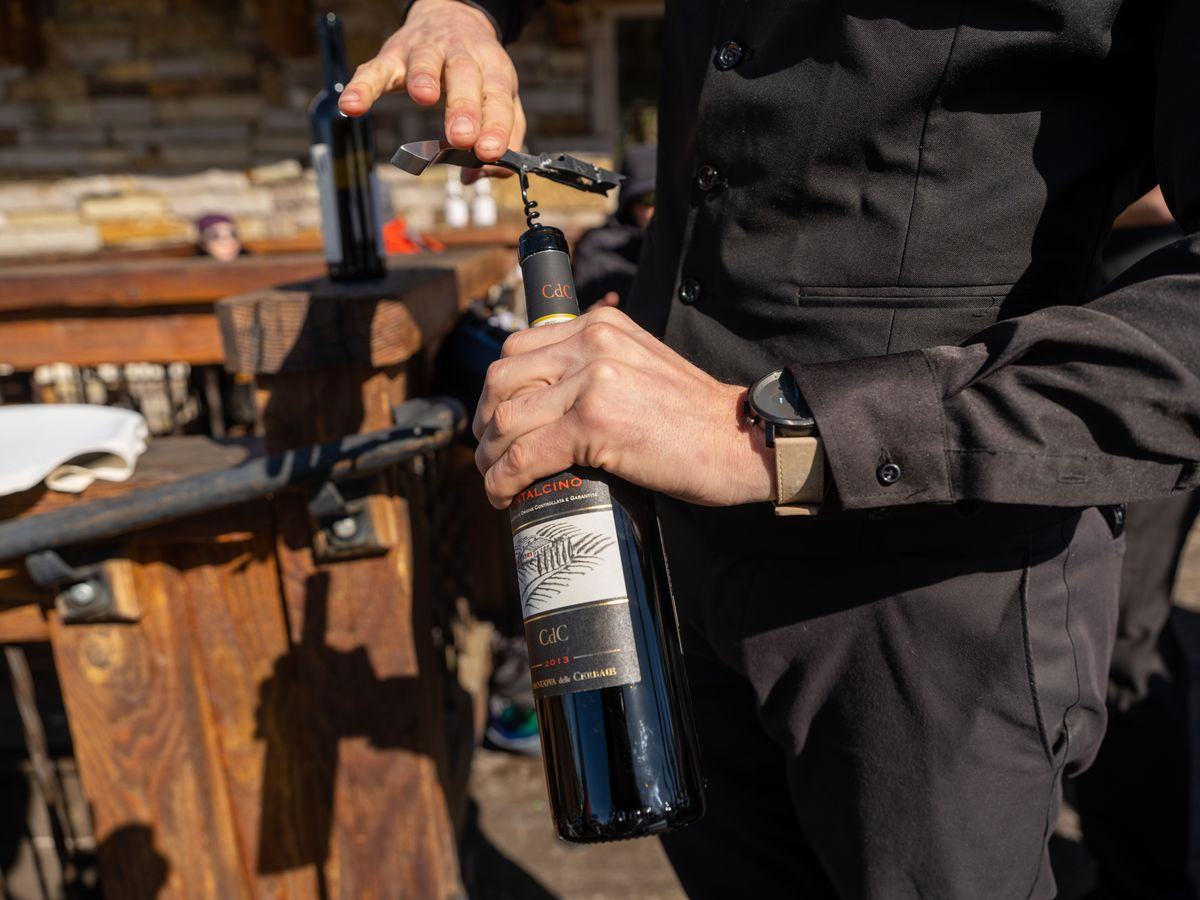 A server opening a bottle of Brunello di Montalcino tableside on the deck at Alpino Vino, Telluride