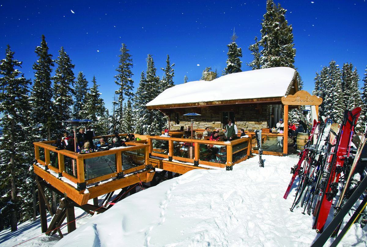 The full deck at Alpino Vino in falling snow, skis racked outside the h&uuml;tte on Gold Hill, Telluride Ski Resort