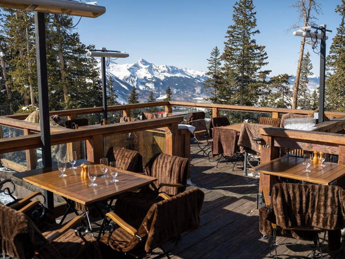 The multi-tiered teak deck at Alpino Vino with sheepskin throws over the chairs and the Wilson Range filling the horizon at 11,966 feet