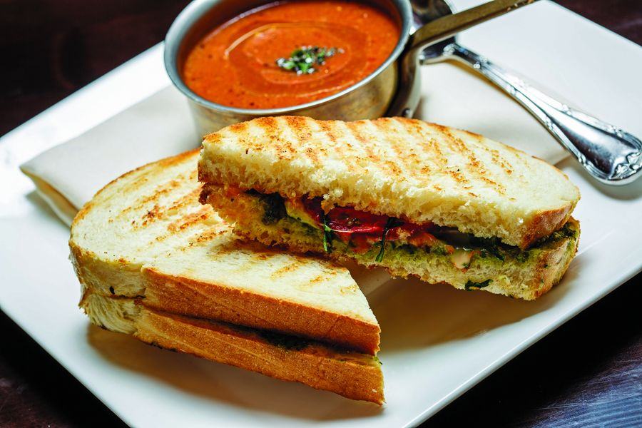 The Alpino Vino signature grilled cheese on Parmesan sourdough, cut open with basil pesto and roasted tomatoes, served with organic tomato-Gorgonzola soup