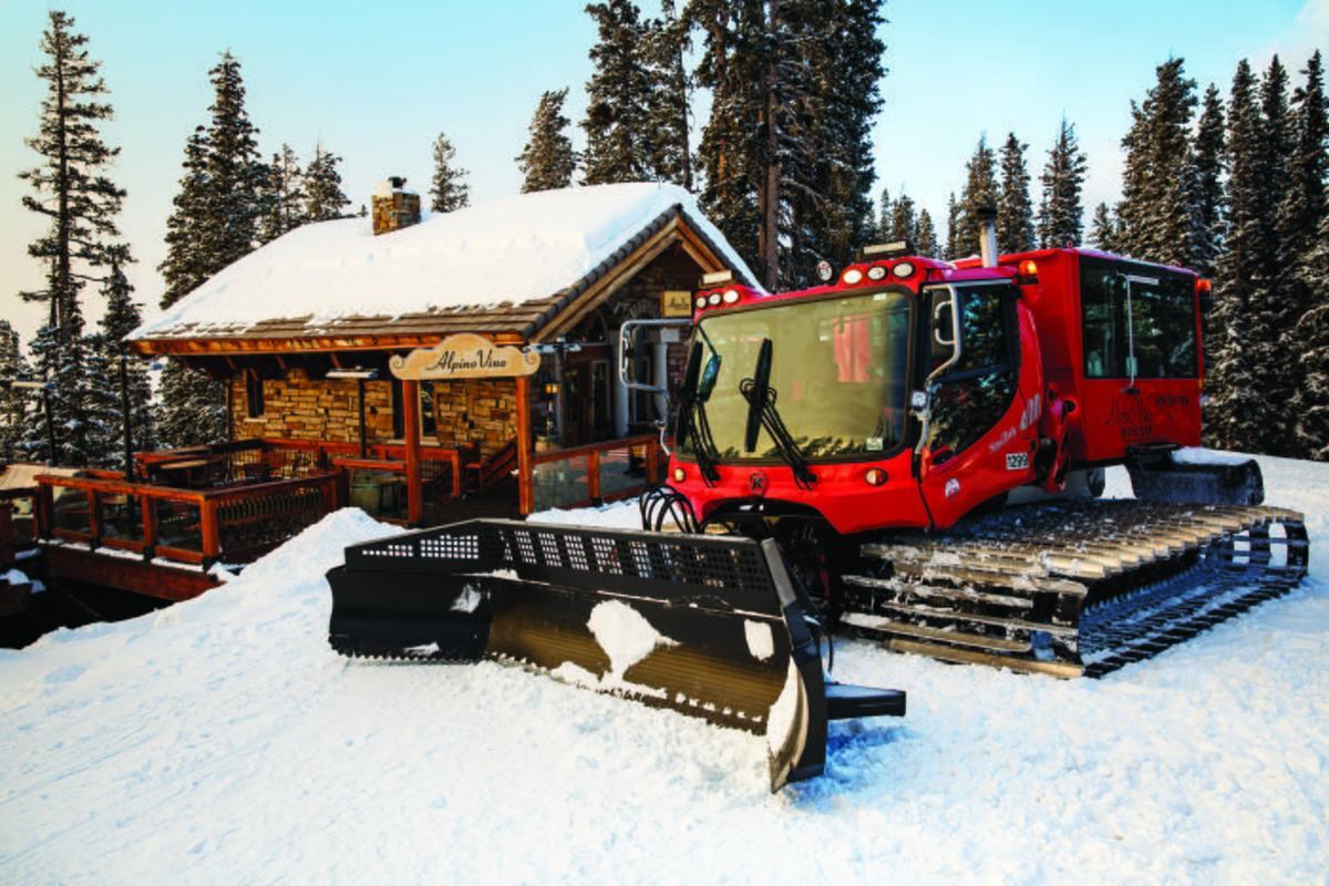The red Alpino Vino Wine Bar snowcoach parked at the door of the h&uuml;tte under deep snow at 11,966 feet on Gold Hill, Telluride Ski Resort