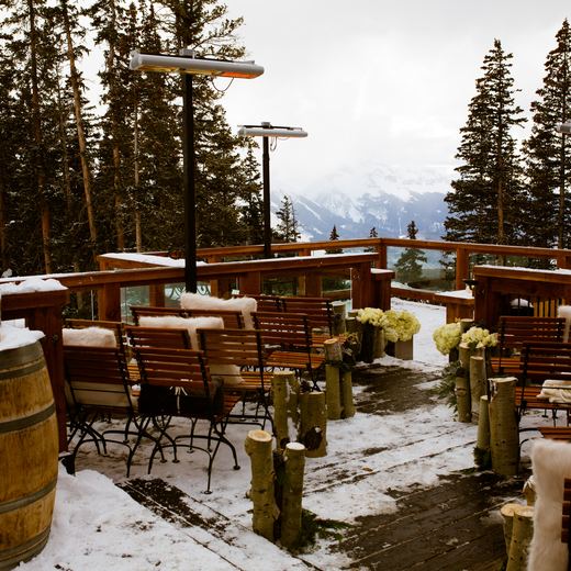 The Alpino Vino deck set for a ceremony: benches with fur throws, birch log markers, hydrangeas and a wine barrel with candles