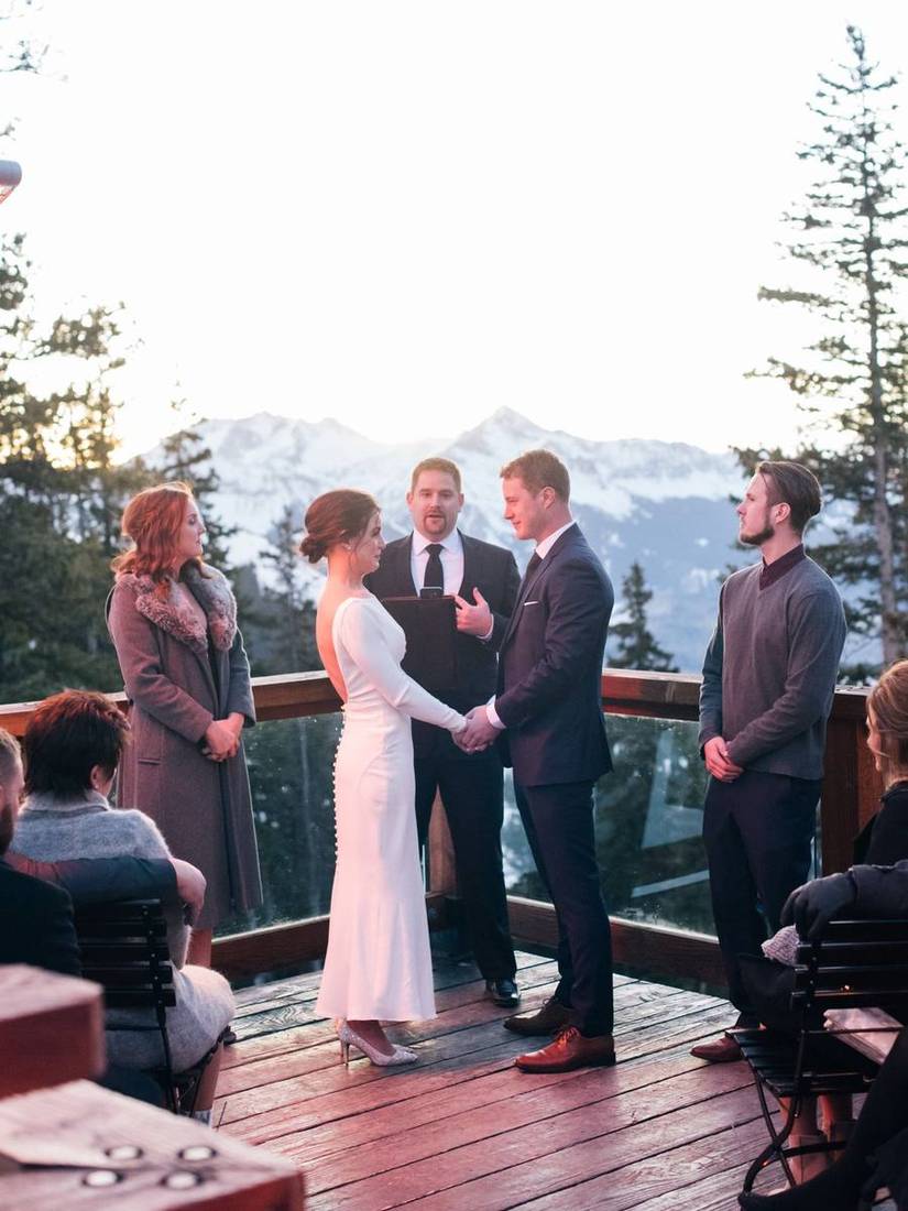 A couple exchanging vows on the Alpino Vino deck at sunset, guests standing either side and Mount Wilson behind, at 11,966 feet above Telluride