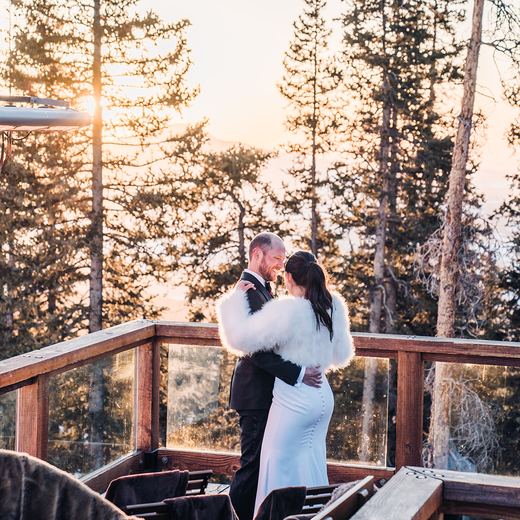 A couple embracing on the Alpino Vino deck in golden evening light at 11,966 feet above Telluride