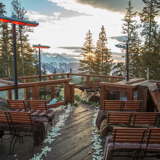 The Alpino Vino deck set for a ceremony at sunset: benches with fur throws, a petal aisle and Mount Wilson beyond
