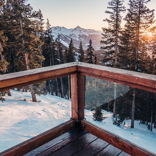 The view from the Alpino Vino deck at sunset: pines, the San Juan peaks and the sun dropping behind the ridge