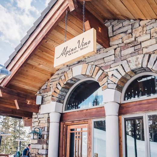 The carved Alpino Vino Wine Bar sign above the stone arches and the deck, Telluride Ski Resort