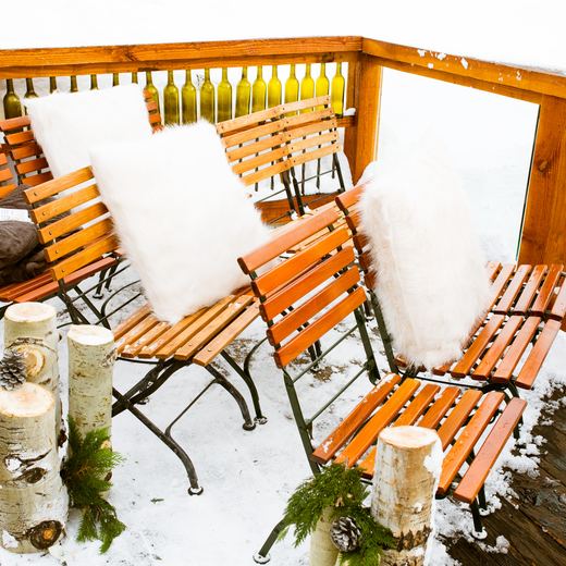 Deck seating at Alpino Vino dressed for a wedding with white fur cushions, birch log markers and the wine-bottle railing