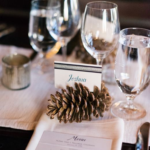 A place setting at Alpino Vino: a calligraphed name card held in a pine cone beside a printed Alpino Vino menu
