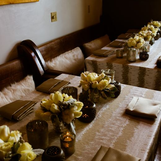 Tables at Alpino Vino set with pale roses, mercury votives and fur throws over the banquette seating
