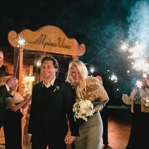 A sparkler send-off under the Alpino Vino sign after dark, guests holding sparklers on both sides